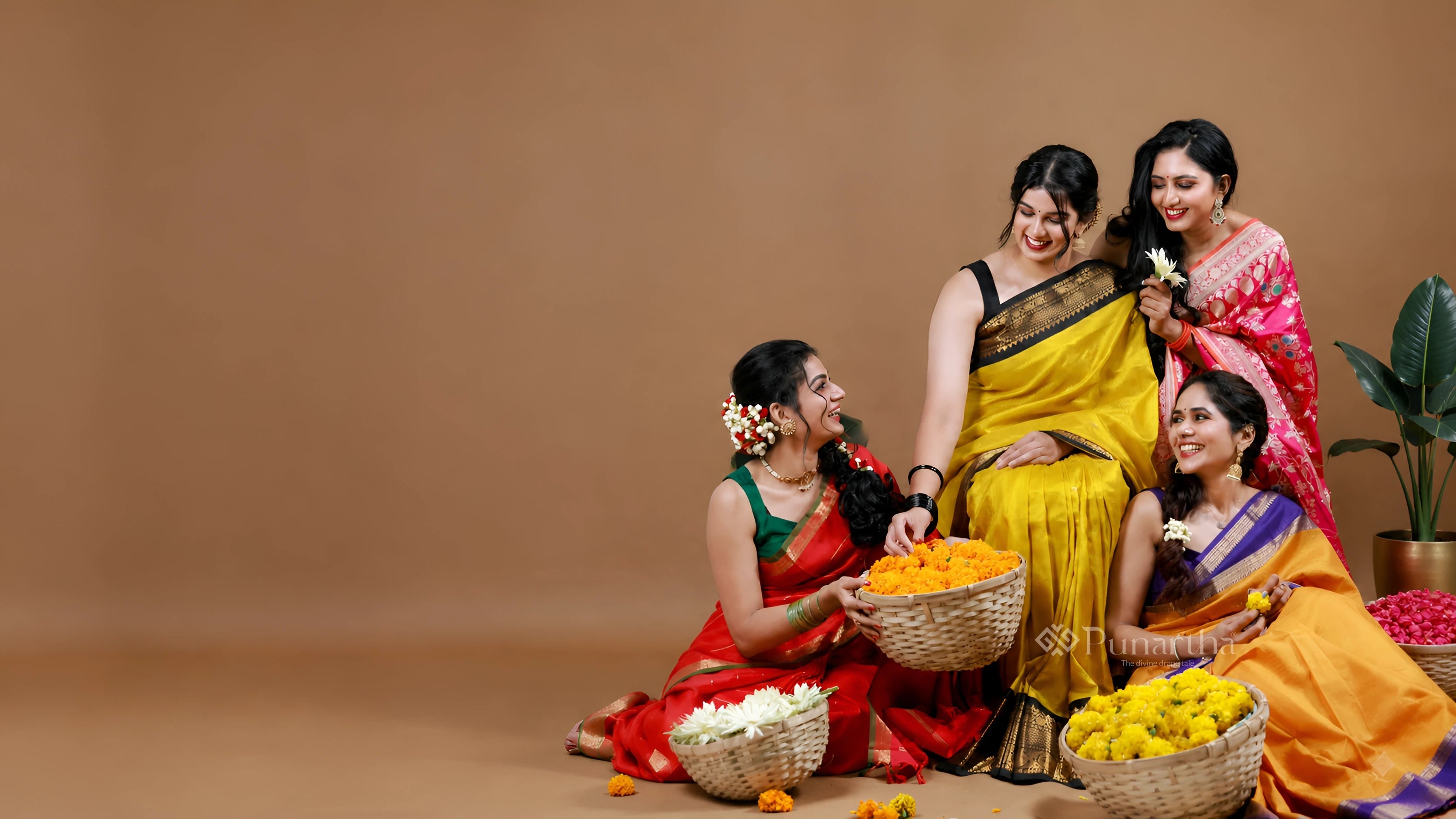 Four women arranging flowers together in colourful handwoven sarees